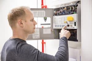 man inspecting a fire alarm control panel in denver